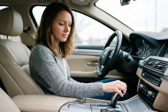 Femme au volant d'une voiture automatique regardant le sélecteur de vitesses avec les positions P R N D visibles